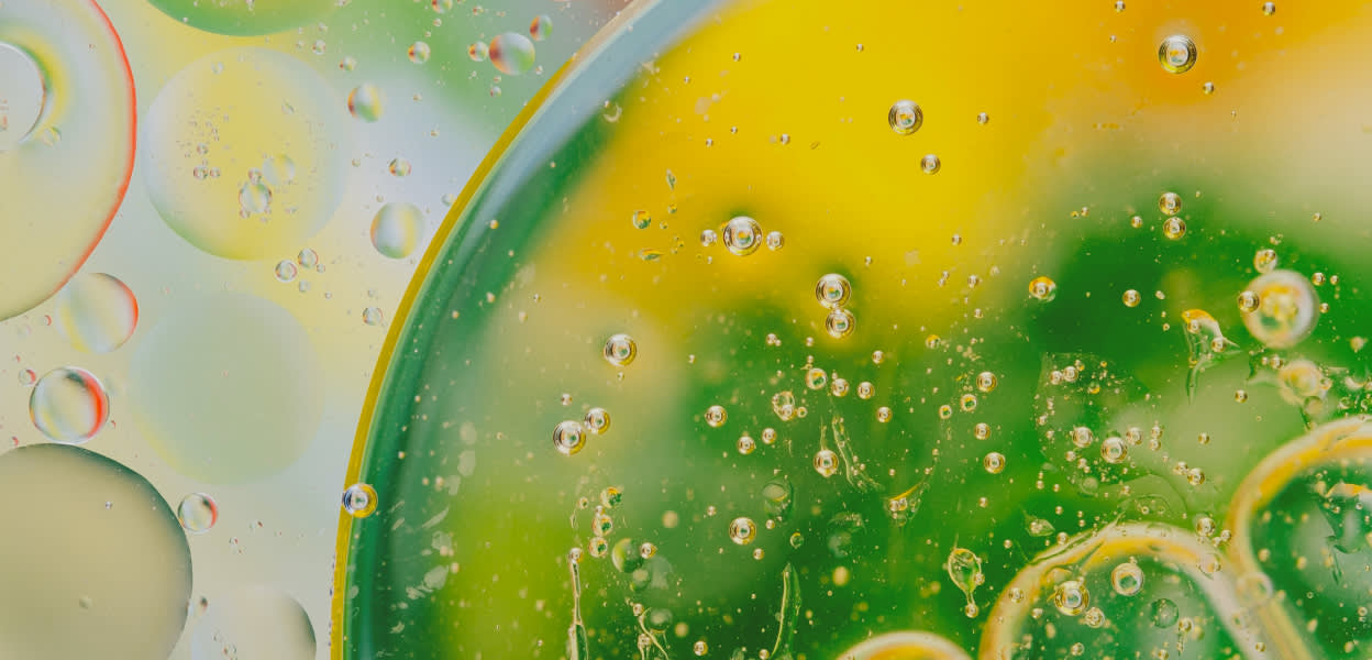 A microscopic view of green and yellow organisms meant to represent bacteria that causes bad breath – Viome Oral Health Intelligence Test